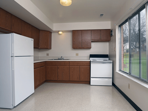 A kitchen with white appliances and brown cabinets.