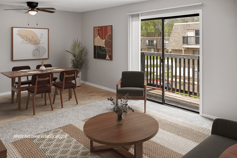 A living room with a dining table and chairs, a ceiling fan, and a view of a balcony with a railing.