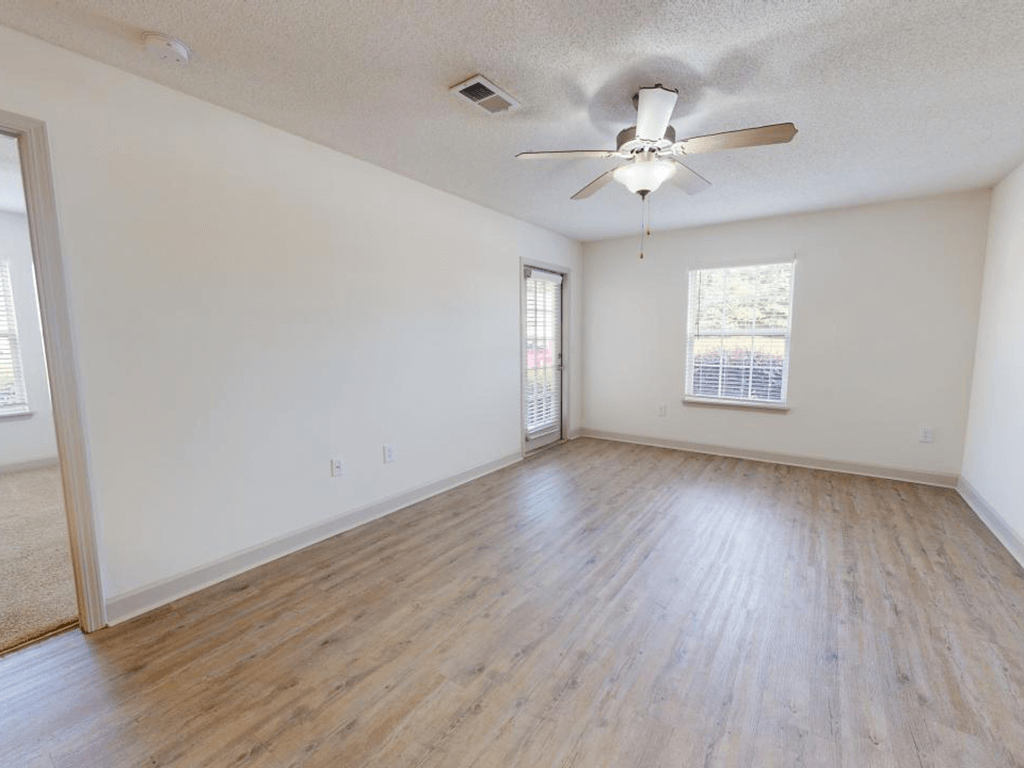 an empty living room with wood floors and a ceiling fan