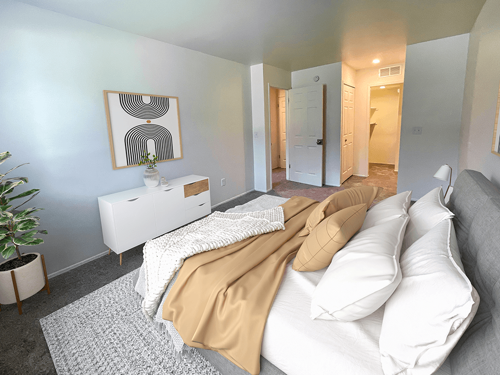 a bedroom with a bed with white pillows and a tan blanket