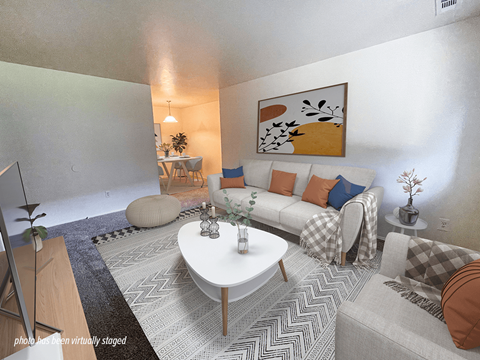 A living room with a white couch, a coffee table, and a painting on the wall.