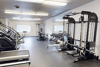 A gym with a variety of equipment including treadmills, weights, and exercise machines.