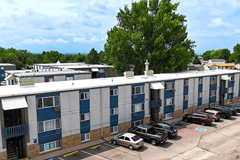 A parking lot in front of a blue and white building with trees.