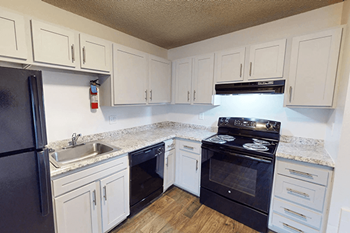 A kitchen with black electric appliances and white cabinets