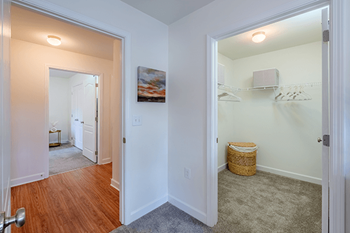 A room with a wooden floor and a white wall with a painting hanging on it.