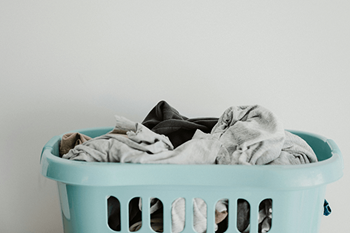 A light blue laundry basket filled with clothes.