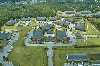 A bird's eye view of a residential complex with a central building and surrounding houses.