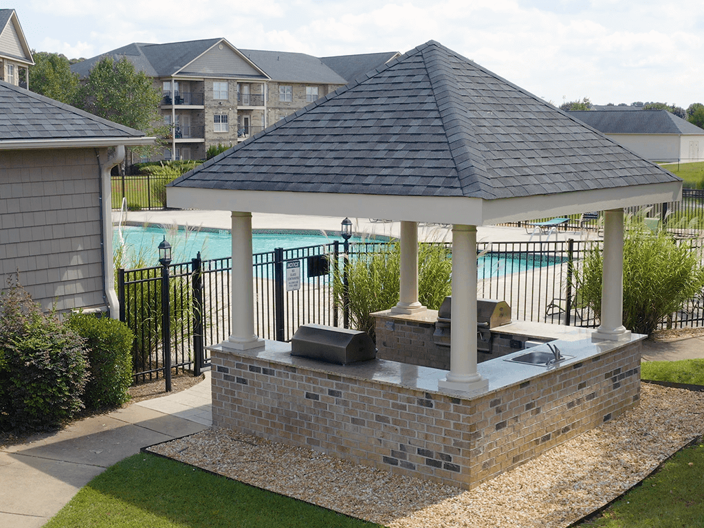 A gazebo with a hot tub sits in a backyard.