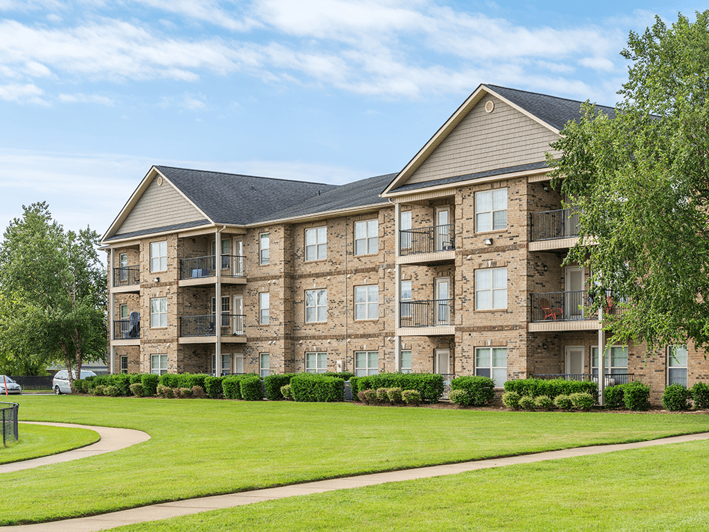 A large apartment building with a grassy area in front.