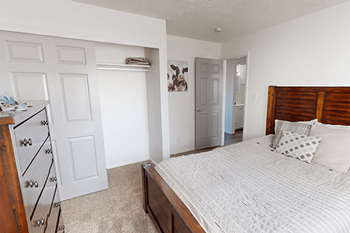 A bedroom with a bed, dresser, and closet.