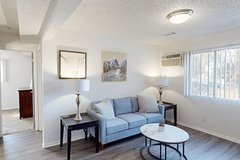 A living room with a grey couch, a white coffee table, and a painting on the wall.