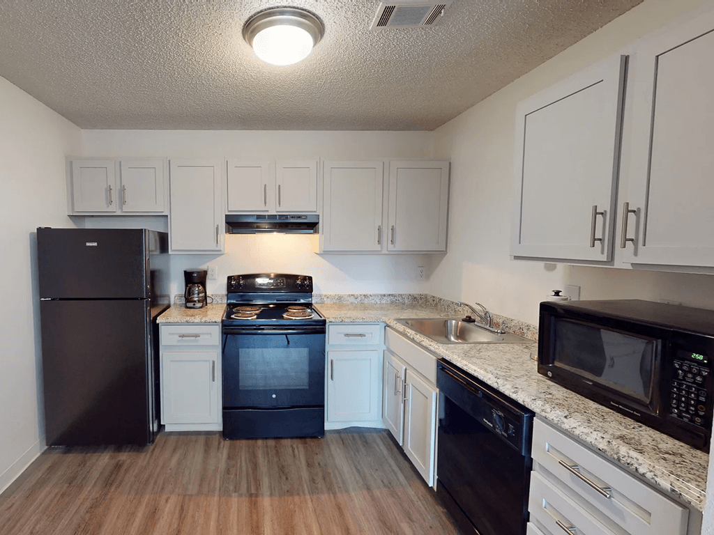 A kitchen with black appliances and white cabinets.