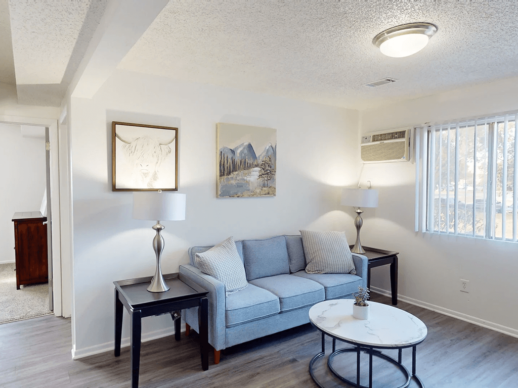 A living room with a grey couch, a coffee table, and two lamps.