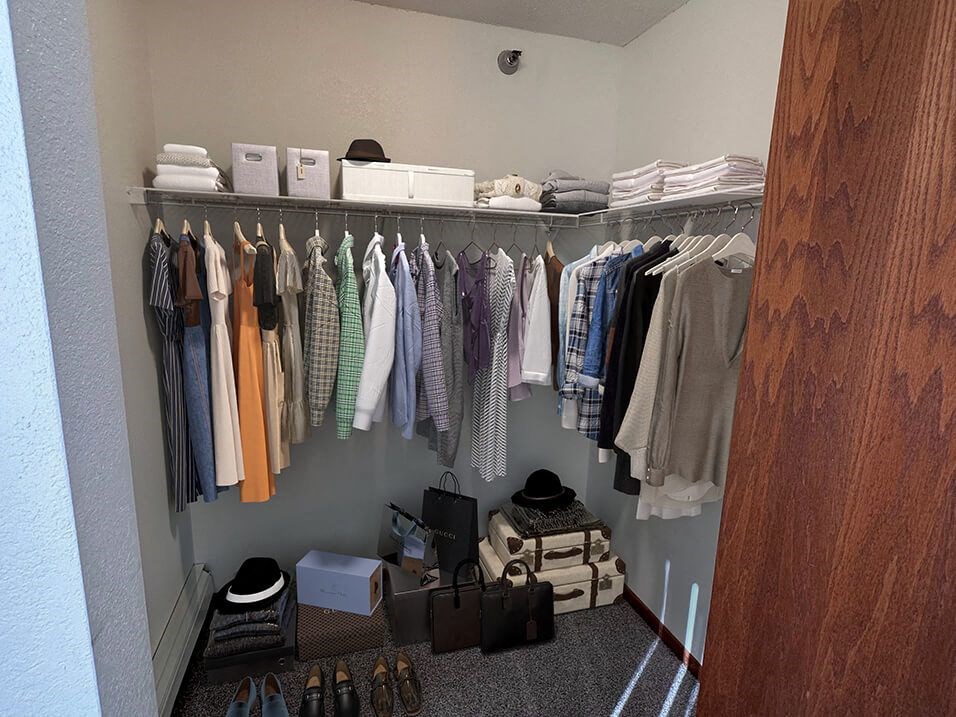 a walk in closet with a rack of clothes and shoes on the floor