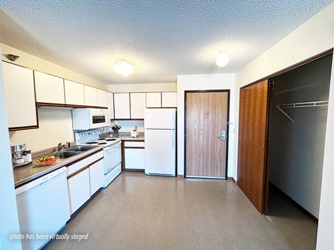 A kitchen with white cabinets and a refrigerator.