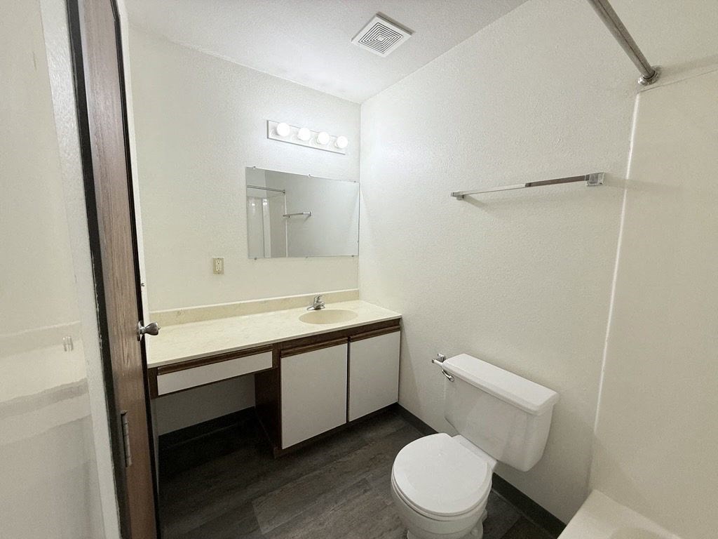 A white toilet sits in a bathroom next to a sink and mirror.
