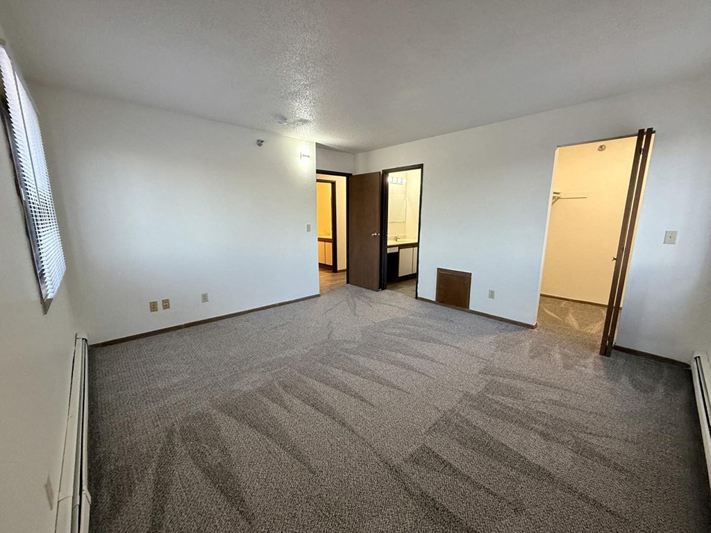 A room with carpeted floor and two doors.