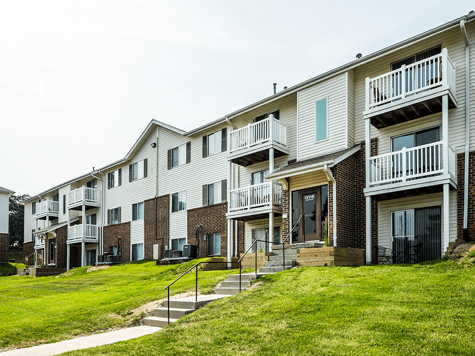 a photo of a row of apartment buildings on a grassy hill