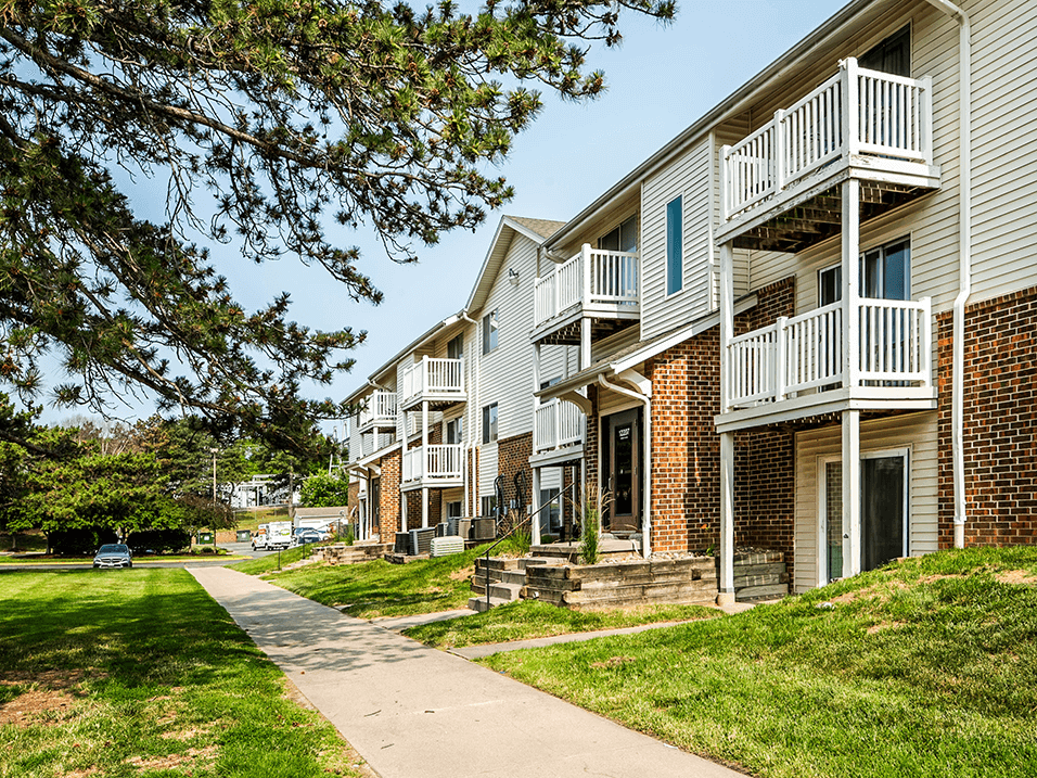 a sidewalk leading to building with balconies