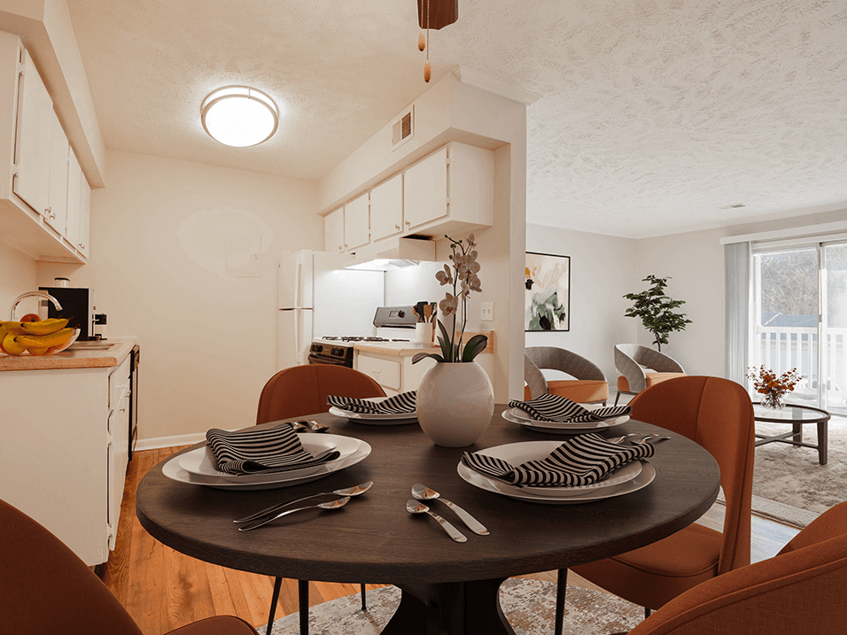 a dining area with a table and chairs and a kitchen in the background