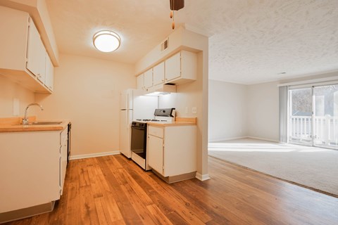 A kitchen with white cabinets and wooden floors.