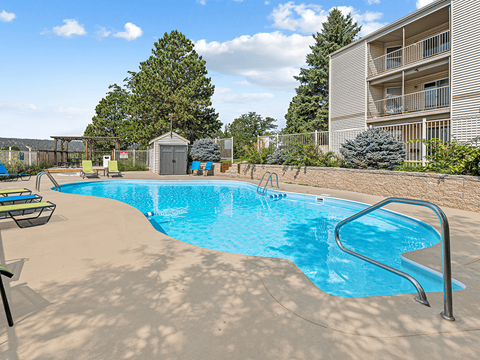 A small pool with a slide and a building in the background.