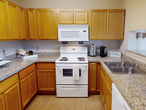 A kitchen with a white stove top oven and a white microwave above it.