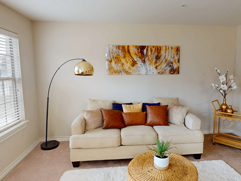 A living room with a white couch, a lamp, and a painting on the wall.