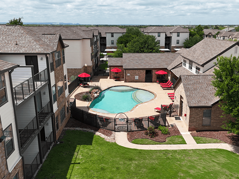 A pool surrounded by a fence and patio furniture.