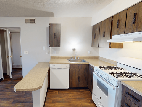 A kitchen with a white stove top oven and a white dishwasher.