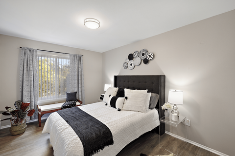 A bedroom with a large bed and a window with curtains.