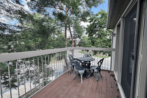 A balcony with a table and chairs overlooking a pool.