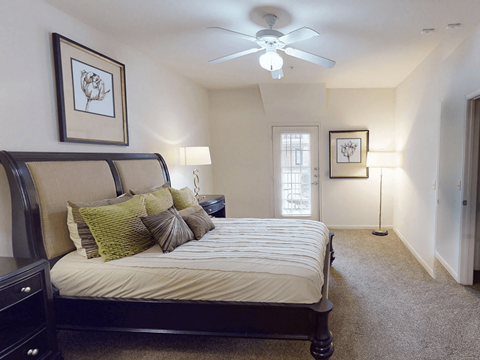 A bedroom with a large bed and a ceiling fan.