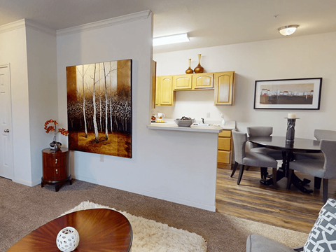 A living room with a painting of trees on the wall.