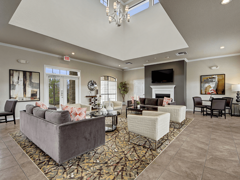 A living room with a grey couch and a chandelier.