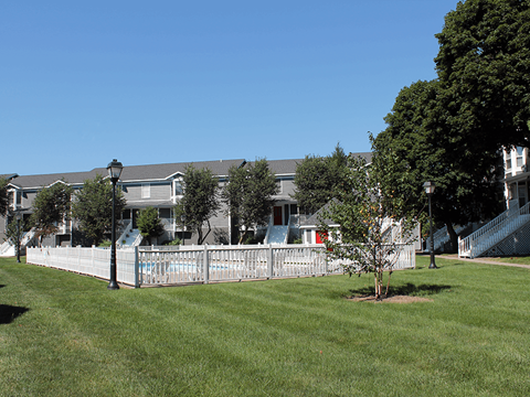 a yard with a white fence in front of a house