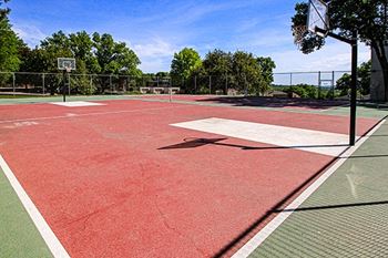 a basketball court on a red court with trees in the background