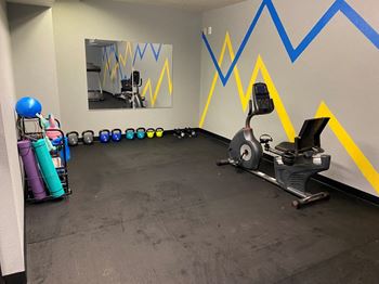 a gym with cardio equipment and a mirror on the wall