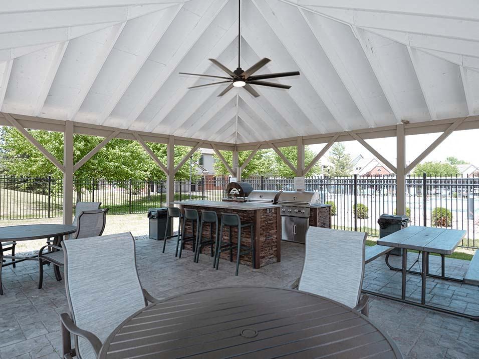 a patio with a table and chairs and a grill