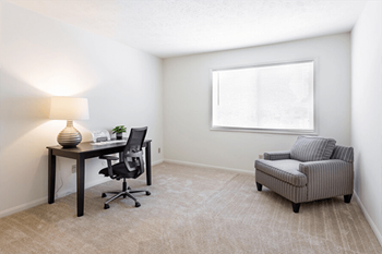 A room with a desk, chair, and a sofa.