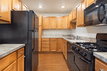 A kitchen with black appliances and wooden cabinets.