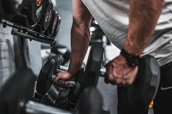 A man is working out with dumbbells in a gym.