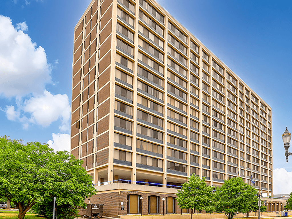 A tall building with many windows and a tree in front of it.