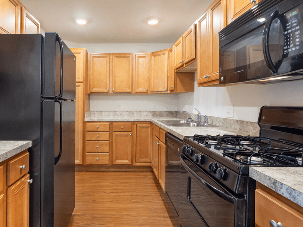 A kitchen with black appliances and wooden cabinets.