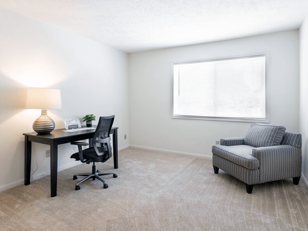 A room with a desk, chair, and a sofa.