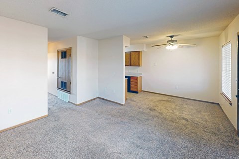A spacious living room with a carpeted floor and a ceiling fan.