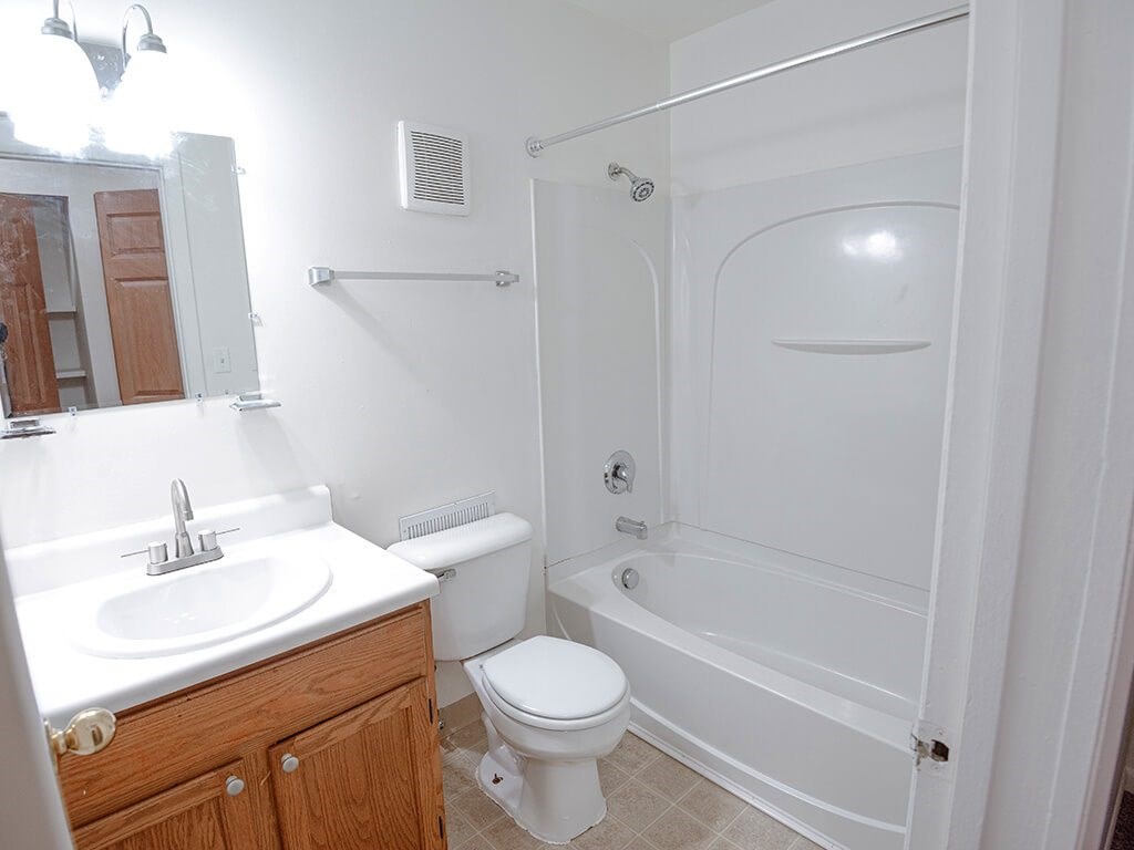 A white bathroom with a toilet, sink, and bathtub.