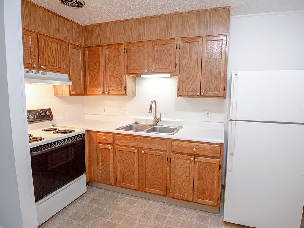 A kitchen with wooden cabinets and a white refrigerator.