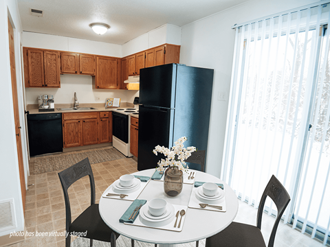 A kitchen with a table set for two and a vase of flowers on the table.