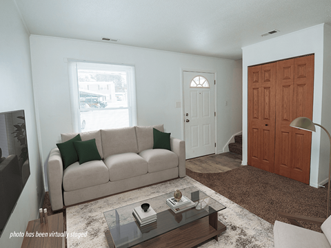 A living room with a couch, coffee table, and a door.